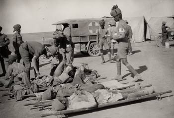 Indian medical orderlies attending to wounded soldiers on stretchers outside a dressing station, Mesopotamia, during the First World War.
