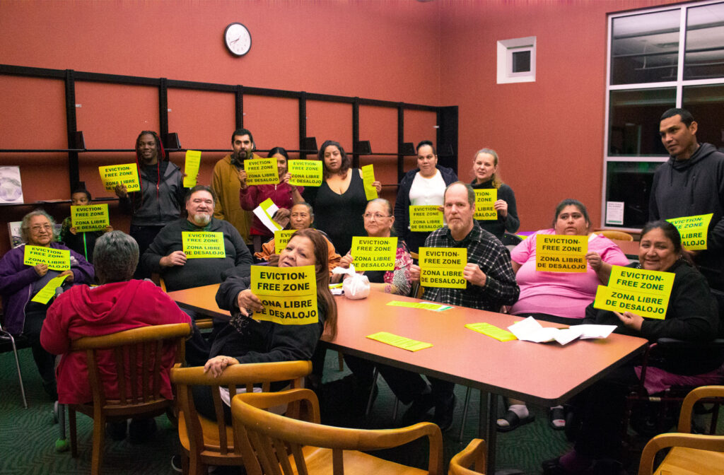 Image of people holding up signs that say Don't Evict