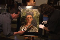 Exhibition Conservator and Head of Exhibition Services Ken Grant and Preparator Wyndell Faulk inspect Frida Kahlo's 'Self-portrait with Thorn Necklace and Hummingbird' in 2009.