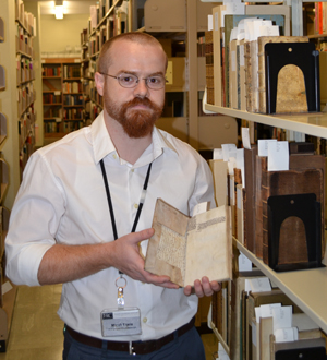Ransom Center Project Archivist Micah Erwin holds one of the books with manuscript fragments that he's hoping to identify through a Flickr site he created. Photo by Alicia Dietrich.