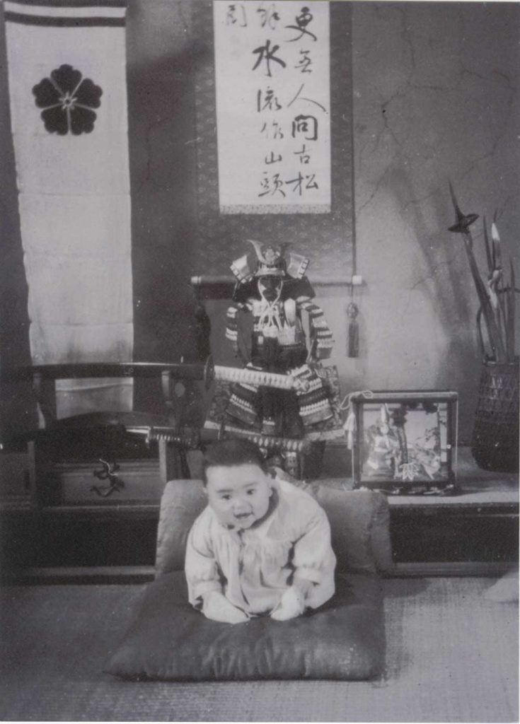Unidentified photographer, [Kazuo Ishiguro as a baby in front of family samurai heirlooms, Nagasaki], ca. 1955. Gelatin silver print, 20.3 x 15 cm. Harry Ransom Center Kazuo Ishiguro Papers.