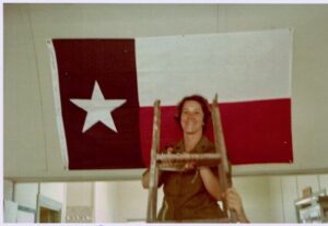 JoAnna hanging the Texas Flag, sent by a Congressman, in her Vietnam Hospital Ward