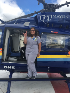 Ashley giving the Hook Em sign while standing on a medical helicopter