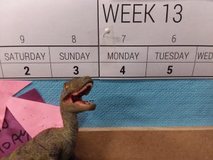 Toy velociraptor posed in front of calendar
