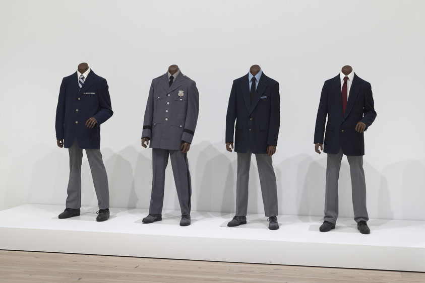 Four headless mannequins positioned on a dais and adorned in different male business suits