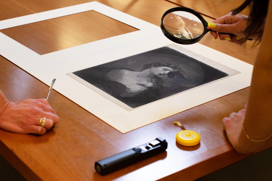 person looking at drawing through magnifying glass