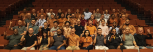 Students sitting in a theatre giving "hook 'em horns" sign