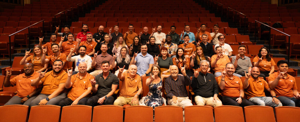 Workshop participants sitting in an auditorium giving the hook 'em sign 