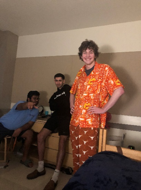 students in orange hawaiian shirt in dorm room