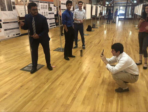 students at their posters, posing for photos