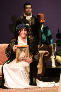 Lady Bertram sits on a couch and holds a portrait of a dog