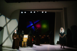 A nun and a woman stand on opposite ends of the stage
