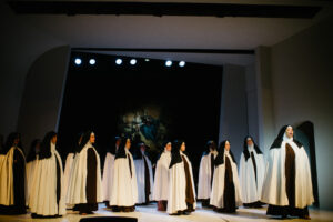 A nun sings as other nuns look on