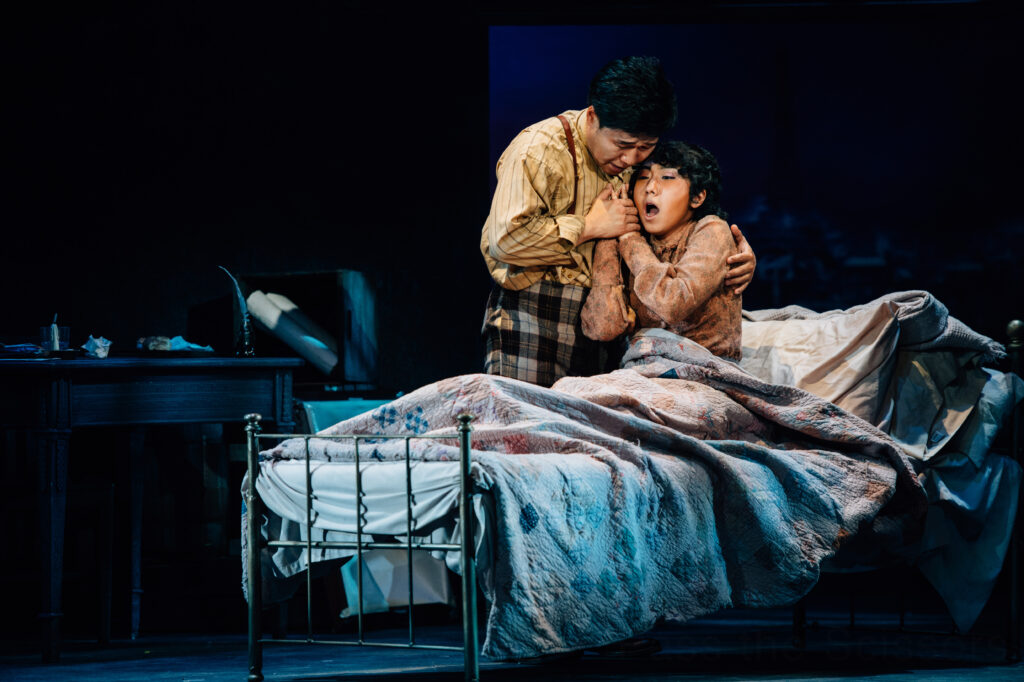 A man and woman embrace in bed, singing together