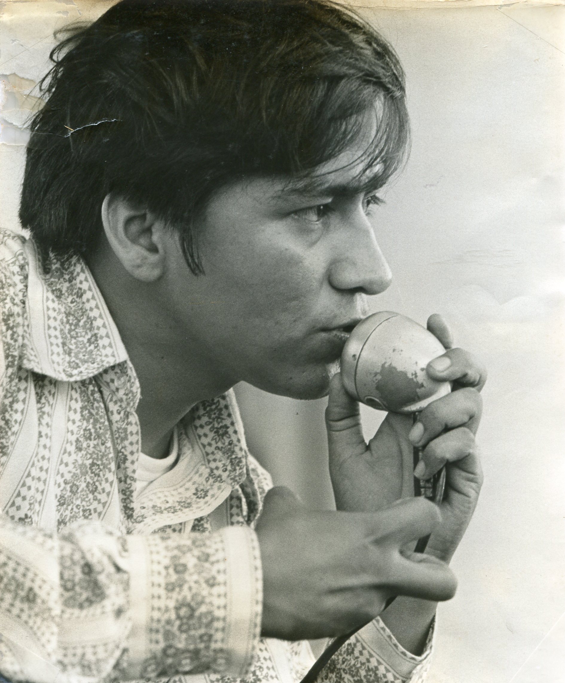 A black and white photo of a man in profile speaking into a microphone.