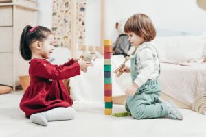 Two toddlers stacking blocks cooperatively
