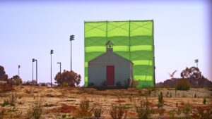 still from digital film by Cauleen Smith titled Remote Viewing showing a white building before a green screen 