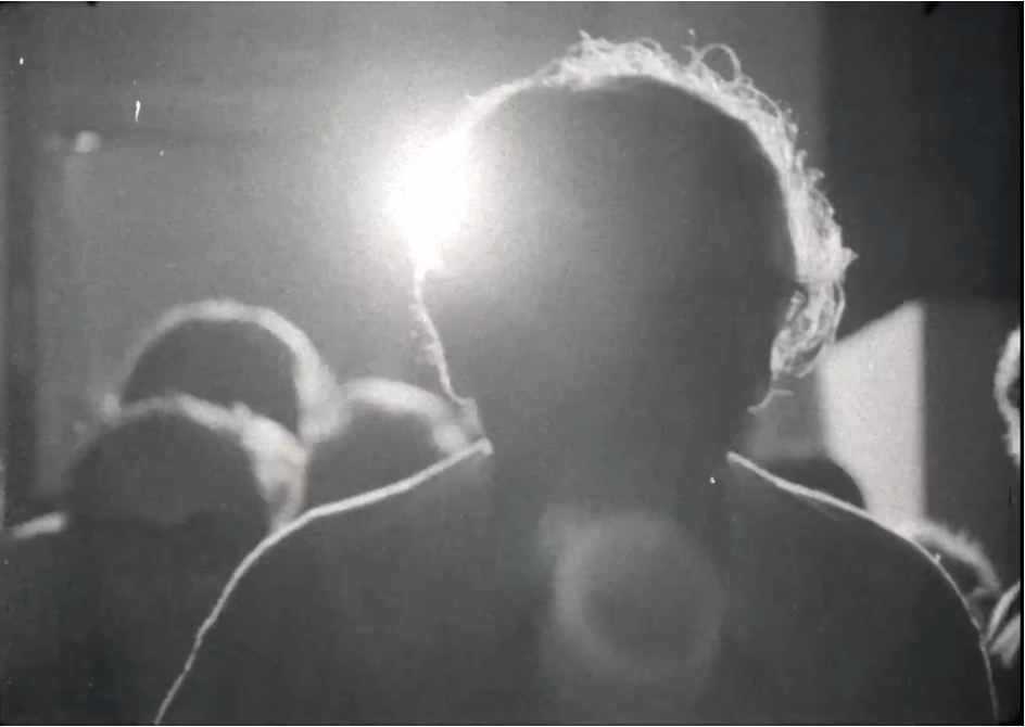 Film still showing a man's bust is backlit so his face is obscured