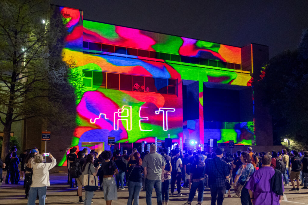 Projection on the side of the Doty Fine Arts Building with the Arts and Entertainment Technologies logo