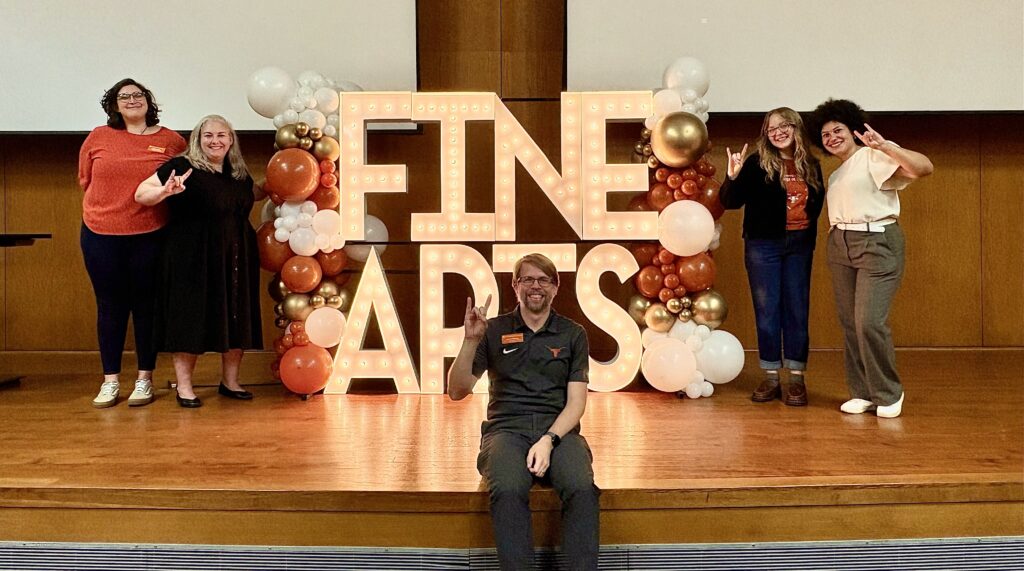 The College of Fine Arts Admissions team standing next to a light up sign that says "Fine Arts"