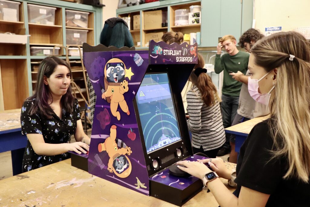 Students playing games design by other students on arcade style systems.