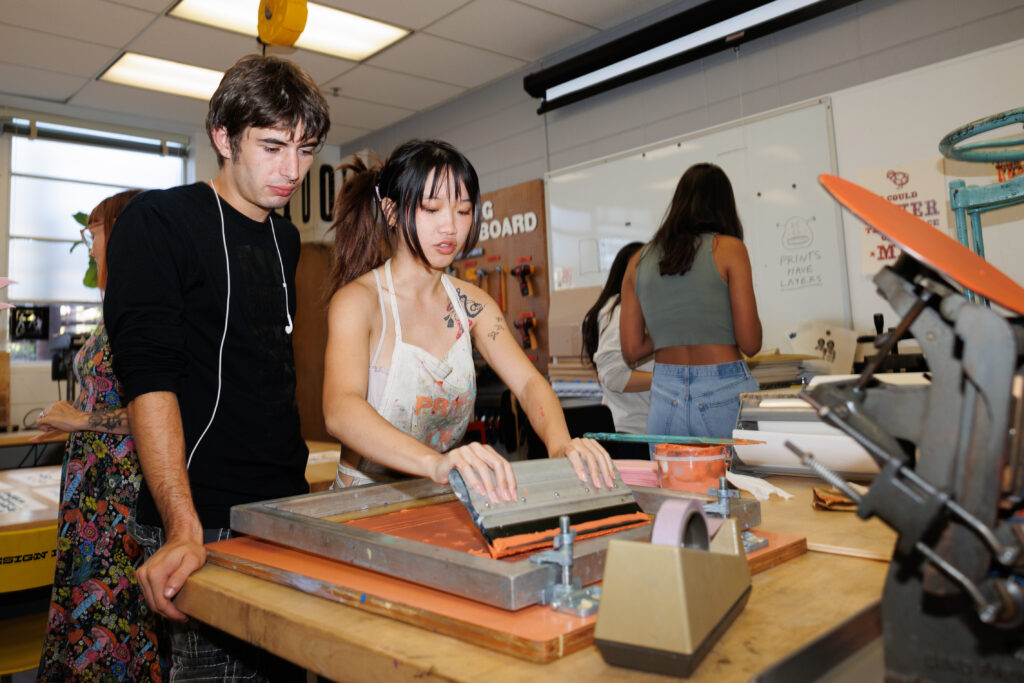 Students using screen printing materials to design a print.