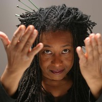 Performance artist and musician pamela z confidently addresses the camera smiling with hands moving outward.