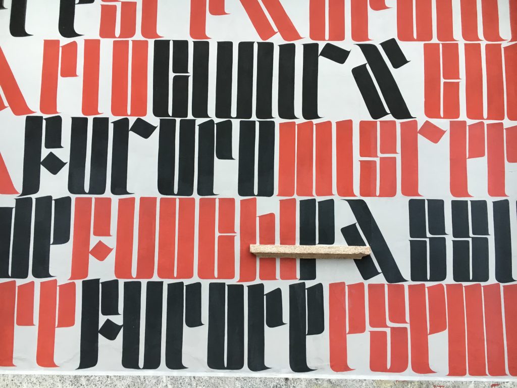 A wall painted next to the mural of faces and a church.