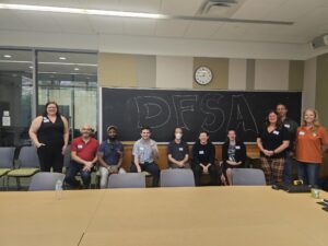 DFSA members pose in front of a blackboard with "DFSA" written in large bubble letters.