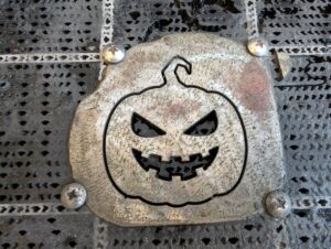 A jackolantern cut into a piece of metal