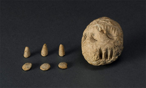 Three small clay discs and three small clay cones with a larger, imprinted clay ball