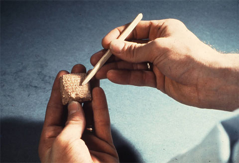 Hands holding a clay tablet