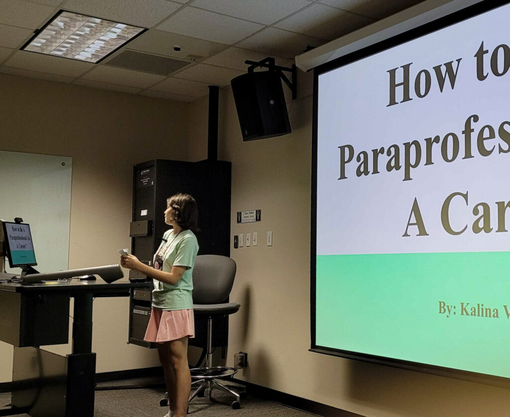 Female student standing in front of a  projector screen giving a speech in her Professional Communications class