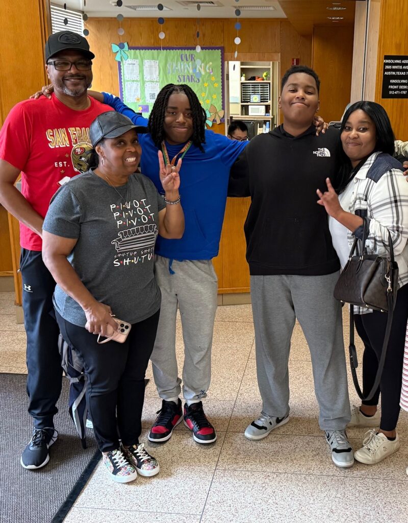 African American family with grandfather, grandmother, two brothers and mom giving the hook em hand sign
