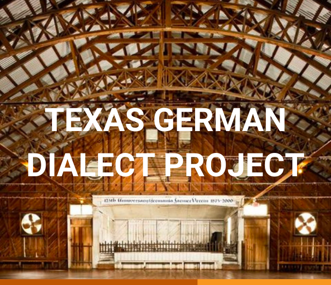 Banner that says "Texas German Dialect Project" written in white. The background shows the Anhalt Hall, a big room with wooden arches and a white stage in the bottom middle. 