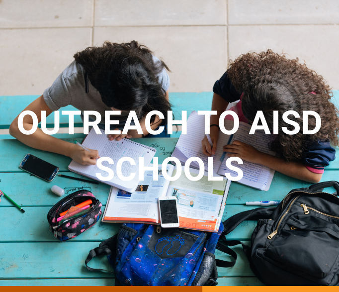 Banner that says "outreach to AISD schools" in white text. The background shows two dark-haired girls from above, doing exercises from a workbook on their notebooks. They're sitting at an aquamarine wooden table, and their backpacks are on the table next to their book, pencilcase and phone.