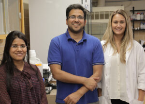 Dr. Ghosh, Rashmi, and Jasmim standing in a lab setting.