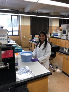 Rashmi wearing a white coat and working in the lab.