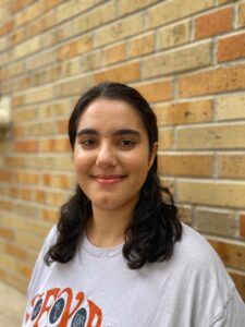 Arian Veyssi smiling and standing in front of a brick wall.