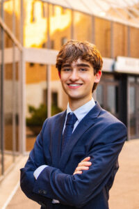 Christopher Salha smiling and standing in front of a building