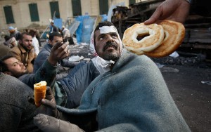 A man who spent the night guarding the barricade around Tahrir Square receives food from a fellow government protester