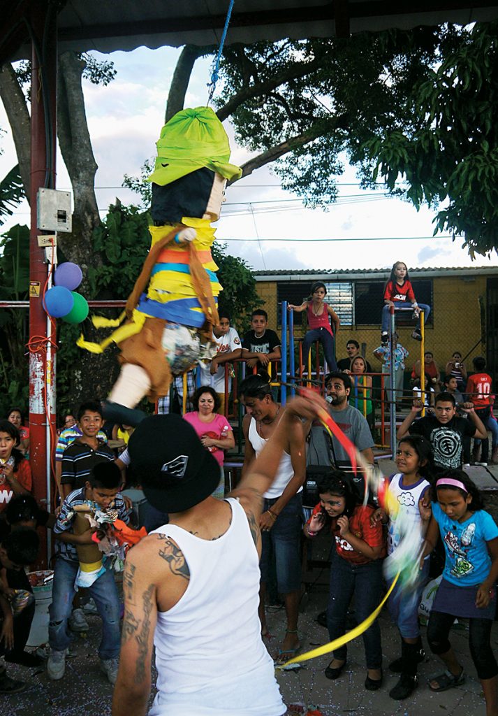A Mara Salvatrucha gang member hits a piñata during a Children's Day celebration in El Salvador, October 2013. The local MS-13 'clica' (loosely formed gang) organized the event for local children. Photo: Ruth Elizabeth Velásquez Estrada.