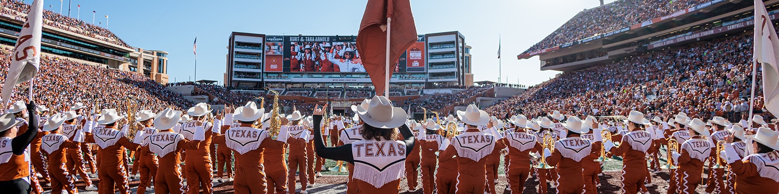 The backs of band members lined up the field 