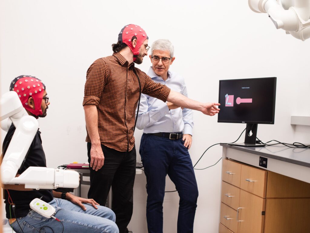 Former students Satyam Kumar and Hussein Alawieh and professor José del R. Millán operate a robotic arm using a brain-computer interface.