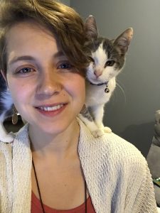 Hannah Salmon poses with a cat perched on her shoulder