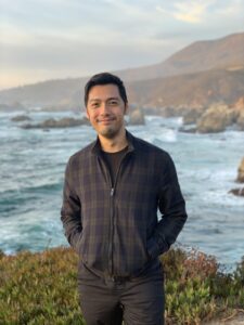 Photo of an Asian-American man, Sherwin Su, in front of an ocean vista