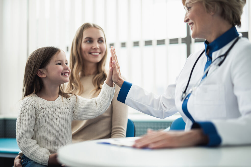 Concept of trustworthy method of consultation in healthcare system. Waist up portrait of smiling little girl giving five to pediatrician lady in medical cabinet
