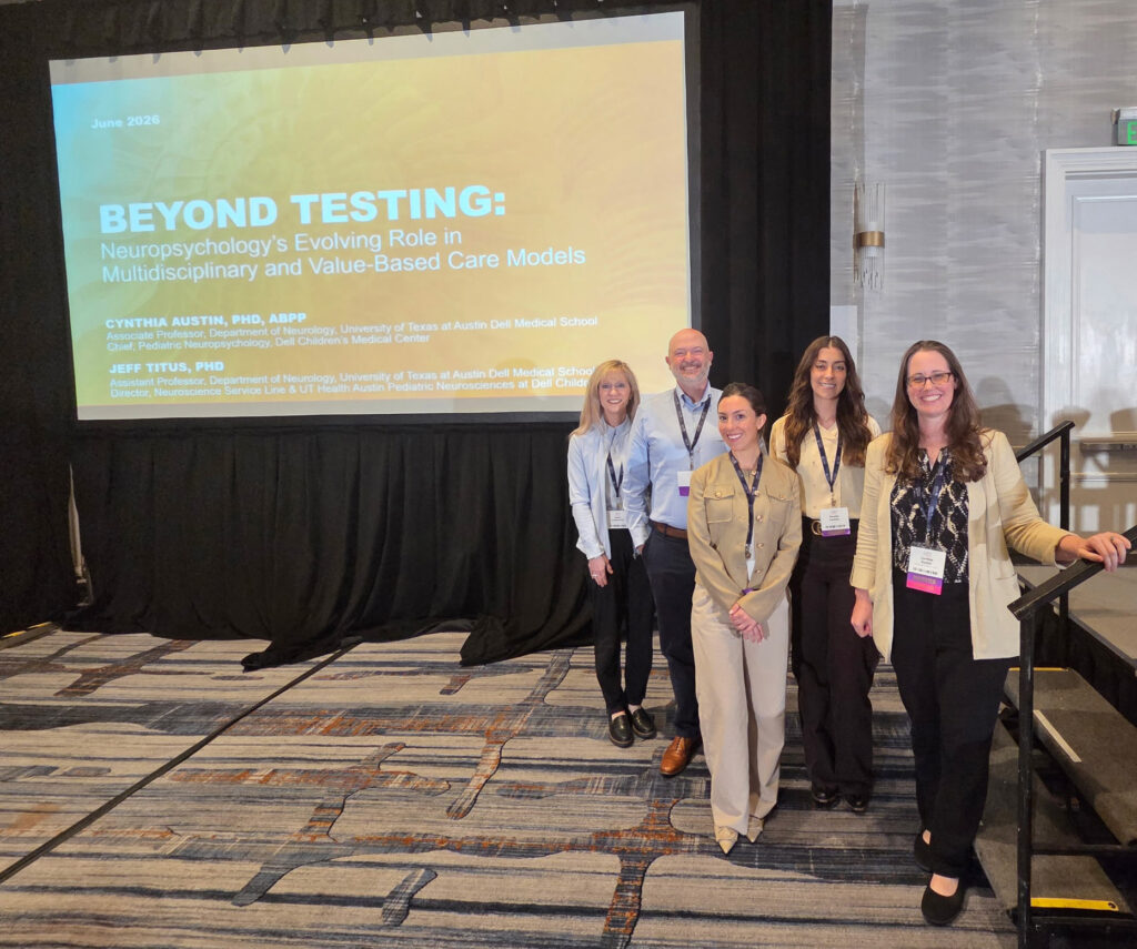Dell Medical School neuropsychology group with presentation backdrop at AACN conference 