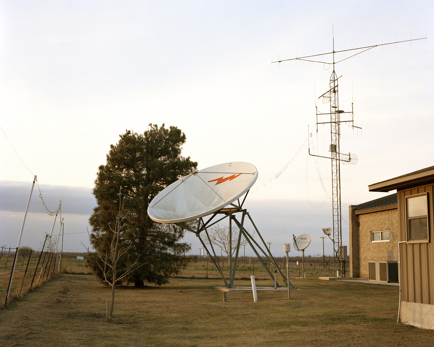 radio signal dish outside of building with adjacent antenna