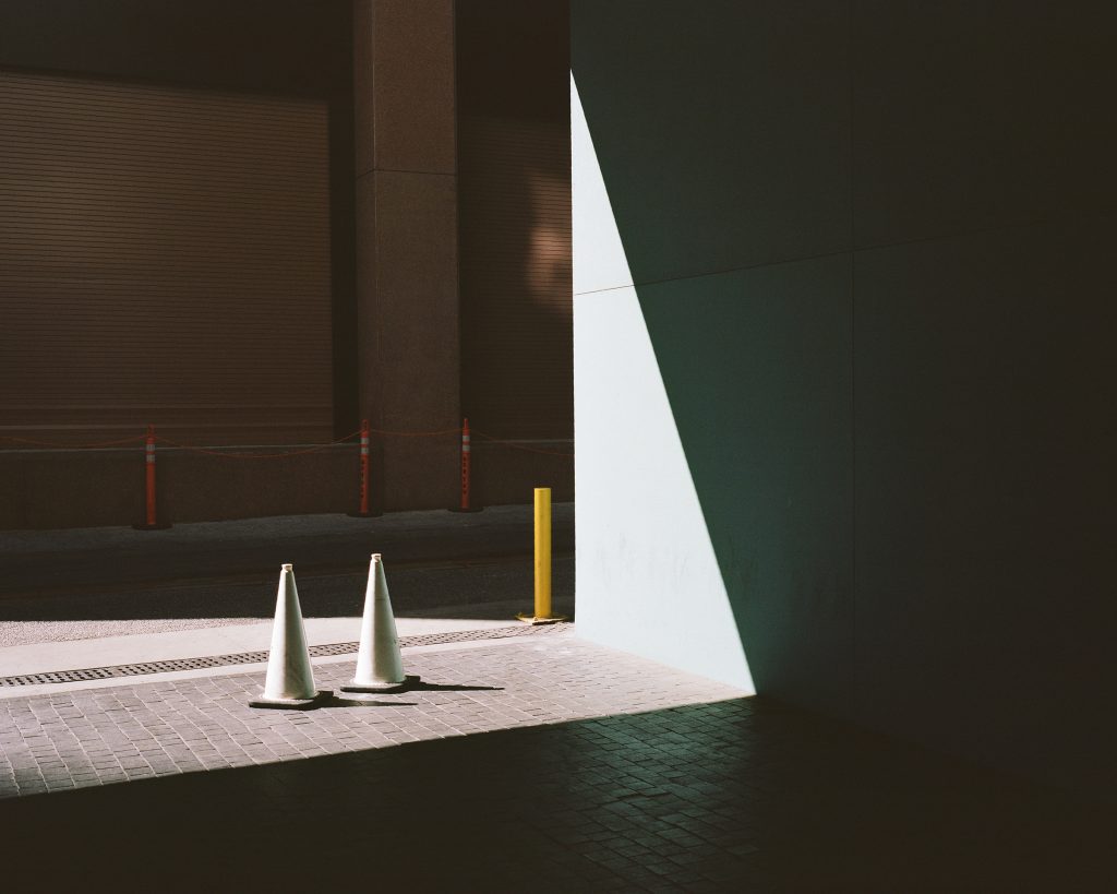 two white traffic cones next to vehicle  pathway in building